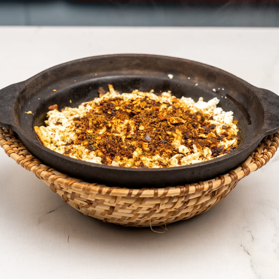 Gazab's Indian dish, a black skillet filled with white and brown crumbled food, served in a woven basket.