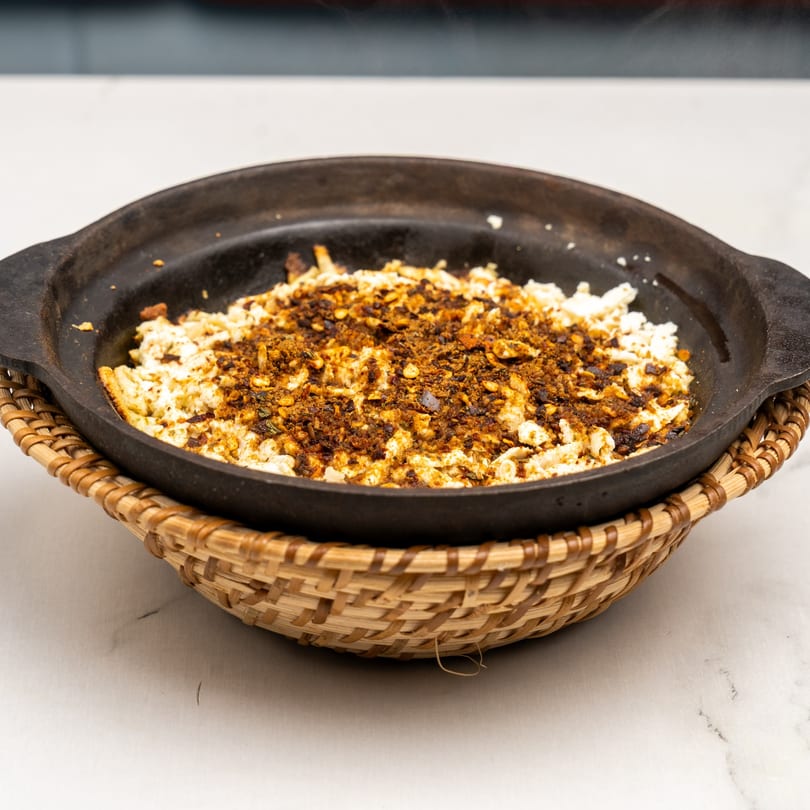 Gazab's Indian dish, a black skillet filled with white and brown crumbled food, served in a woven basket.