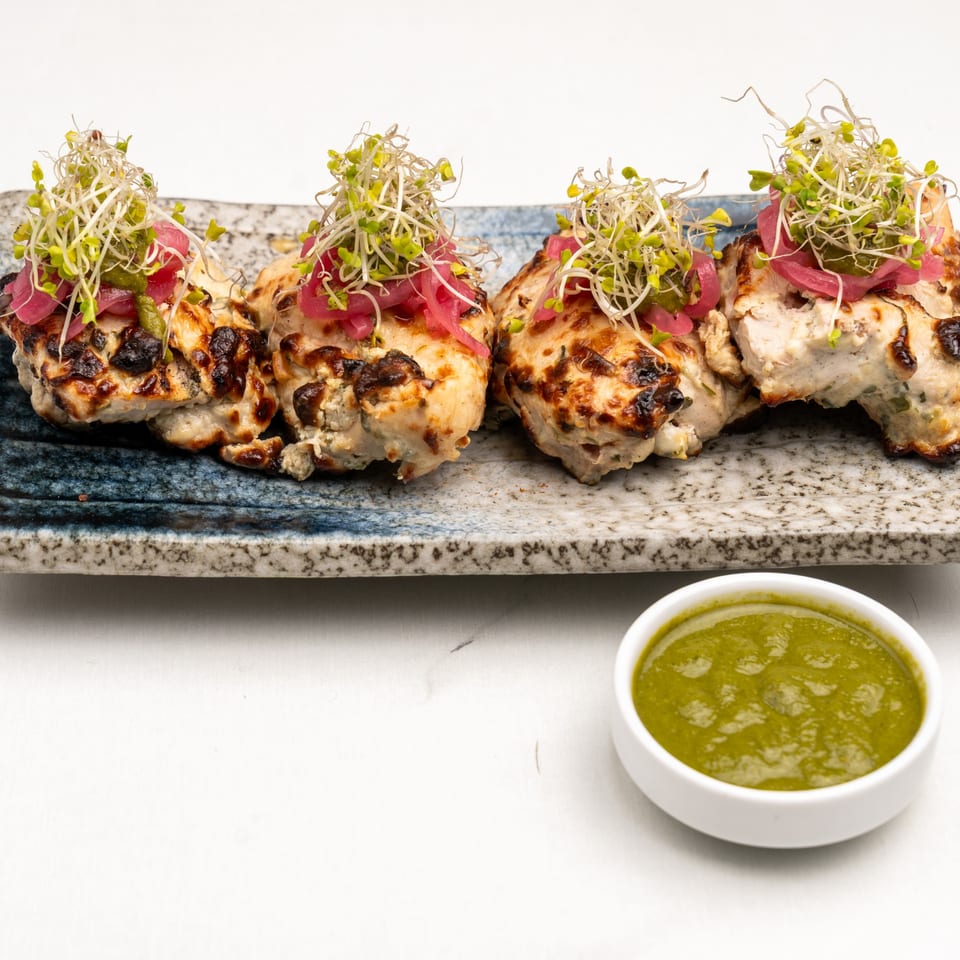 Four pieces of grilled Indian chicken tikka, garnished with sprouts and pickled onions, with green chutney.